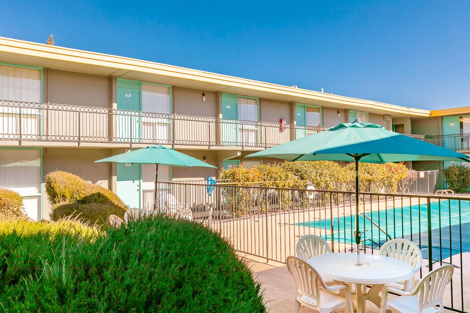 Two-story apartment building with umbrellas and landscaping beside the pool at Uptown Horizon Apartments
