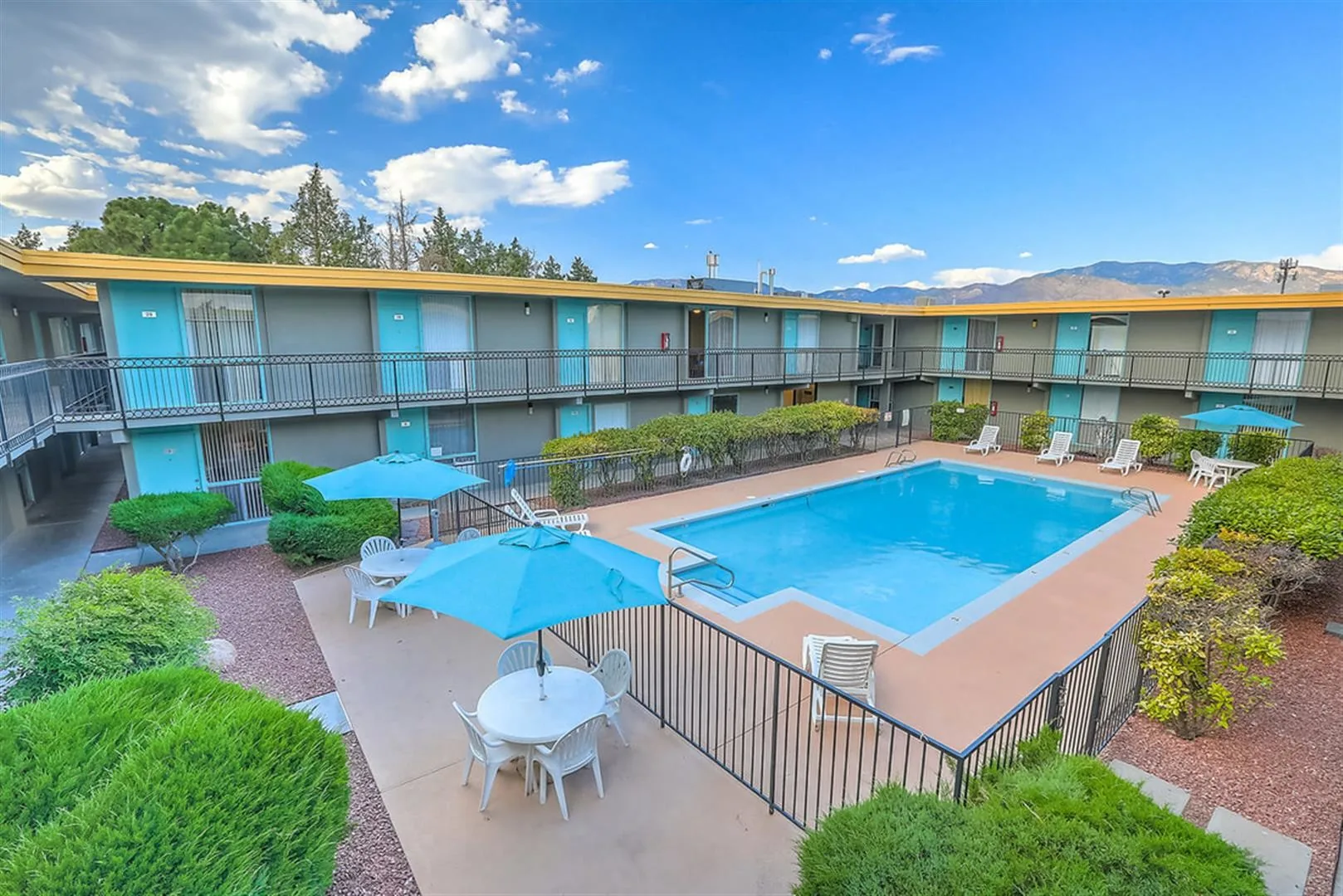 Swimming pool with blue umbrellas in the central courtyard of Uptown Horizon Apartments, Albuquerque, with the Sandia Mountains beyond